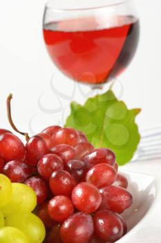 bowl of red and white grapes and glass of red wine or grape juice