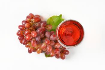 bunch of red grapes and glass of red wine on white background