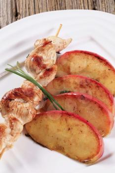 Chicken skewer and slices of baked apple