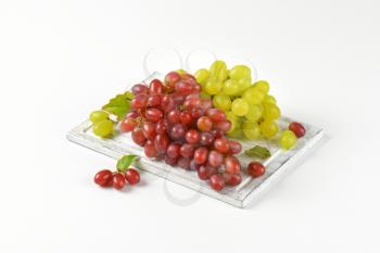 bunches of red and white grapes on wooden cutting board