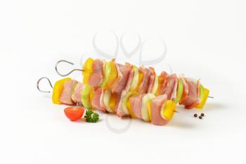 Two raw pork and vegetable skewers