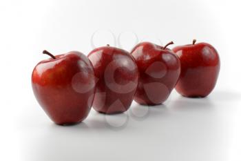 four glossy red apples in a row