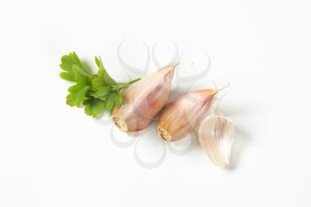 cloves of fresh garlic with parsley on white background