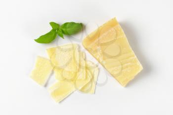 sliced parmesan cheese and basil on white background