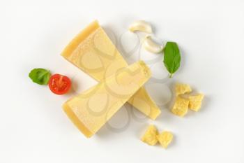 wedges and pieces of parmesan cheese on white background