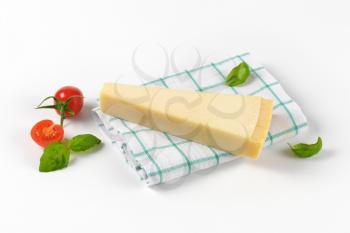 wedge of fresh parmesan cheese and cherry tomatoes on checkered dishtowel