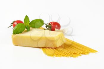 wedge of fresh parmesan cheese, vegetables and spaghetti on white background