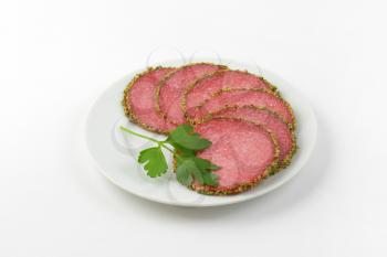 slices of green pepper coated salami on white plate
