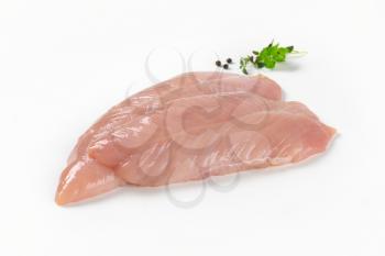 raw turkey breast fillets with spice and herbs on white background
