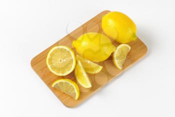whole and sliced lemons on wooden cutting board