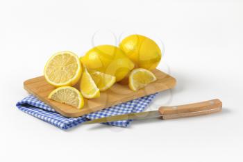 whole and sliced lemons on wooden cutting board