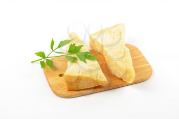 Two wedges of true Parmesan cheese on cutting board