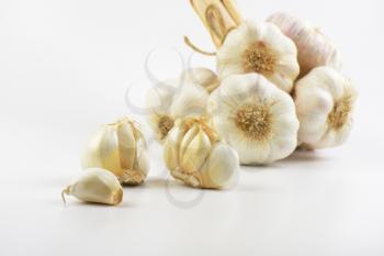 close up of garlic bulbs and cloves on white background