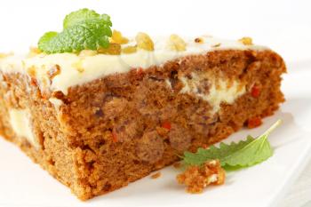 Carrot cake with cream cheese icing topped with chopped walnuts