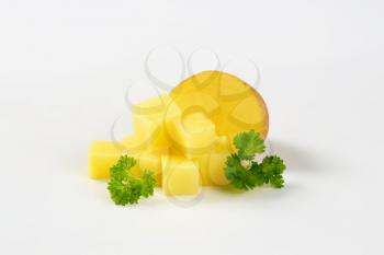 halved and diced raw potato with parsley on white background