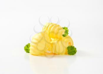 pile of butter curls with green parsley on white background