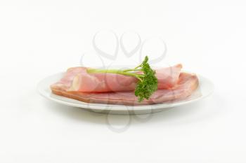 plate of fresh pork ham with parsley on white background
