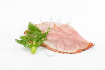 slices of ham and twig of fresh dill on white background