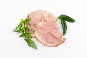 slices of ham and chili peppers on white background