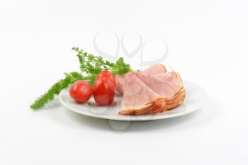 plate of ham slices with fresh dill and cherry tomatoes on white background