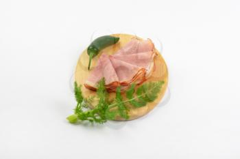 slices of ham and green chili pepper on oval wooden cutting board