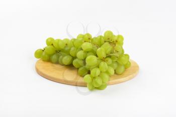 bunch of white grapes on round wooden cutting board