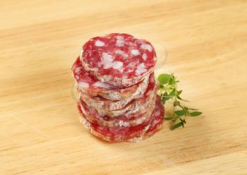 thin slices of dry cured sausage on wooden background