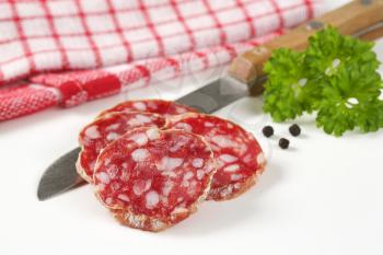 thin slices of dry cured sausage and kitchen knife