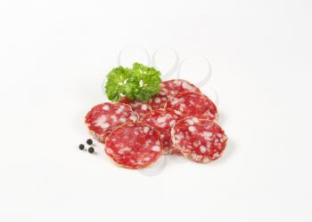 thin slices of dry cured sausage on white background