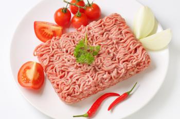 raw minced meat with vegetables on white plate
