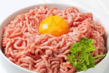 close up of raw minced meat with egg yolk in white bowl