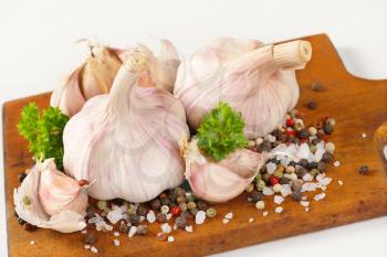 fresh garlic with spices on wooden cutting board - close up