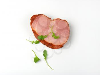 stack of sliced smoked pork meat with arugula leaves on white background