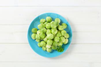plate of raw Brussels sprouts on white background