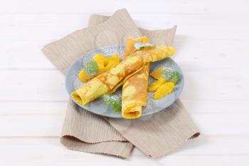plate of thin pancakes (crepes) with fresh orange slices