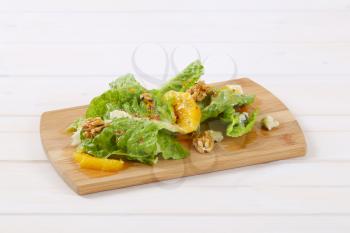 Chinese cabbage salad with orange, walnuts and blue cheese on wooden cutting board