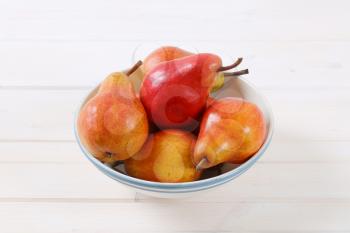 bowl of ripe red pears on white background