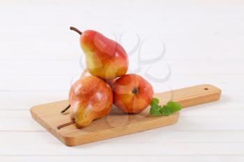 ripe red pears on wooden cutting board