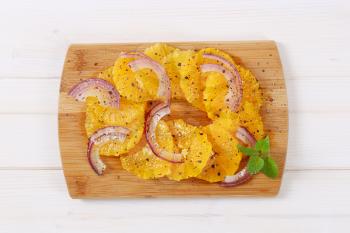 Sicilian orange salad with onion and pepper  on wooden cutting board