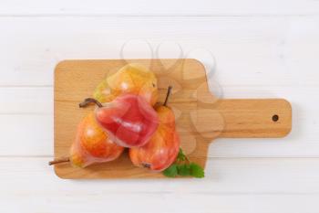 ripe red pears on wooden cutting board
