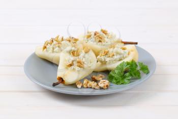 plate of halved pears with blue cheese and walnuts on white background