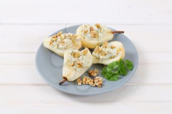 plate of halved pears with blue cheese and walnuts on white background