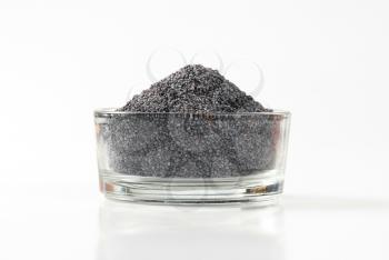 Whole black poppy seeds in glass bowl