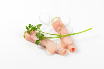 slices of asparagus coated ham rolled on white background