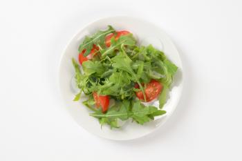 plate of arugula and tomato salad on white background