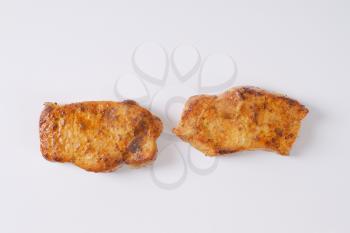 two slices of roasted pork meat on white background