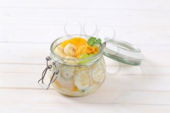 jar of corn flakes with milk and fresh fruit on white background