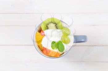 cup of fresh fruit salad with white yogurt on white background