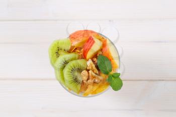 glass of corn flakes with milk and fresh fruit on white background