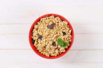 bowl of granola with hazelnuts and raisins on white wooden background